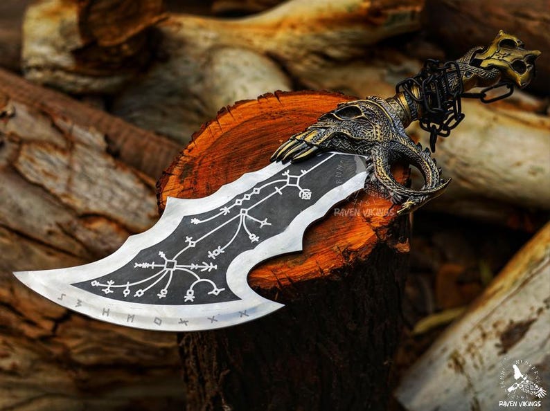 May include: A detailed, decorative knife with a skull-shaped handle and a blade featuring intricate patterns and runes. The handle is gold-colored, and the blade is silver and black. The knife rests on a wooden surface, showcasing its craftsmanship.