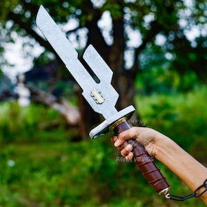 May include: A silver-colored sword with a unique blade design and a brown leather-wrapped handle. The sword has a decorative gold-colored element near the handle. The image is set against a blurred green background.
