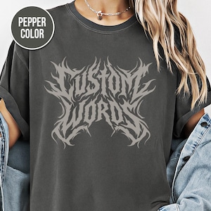 Puede incluir: Camiseta color pimienta con el texto "CUSTOM WORDS" en una fuente gris estilizada. El diseño tiene una estética gótica o metal. La camiseta es de color gris oscuro.