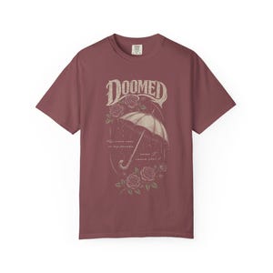 brick color Comfort Colors T-shirt featuring a vintage gothic umbrella illustration with roses and rain details and the word “Doomed” in distressed lettering.