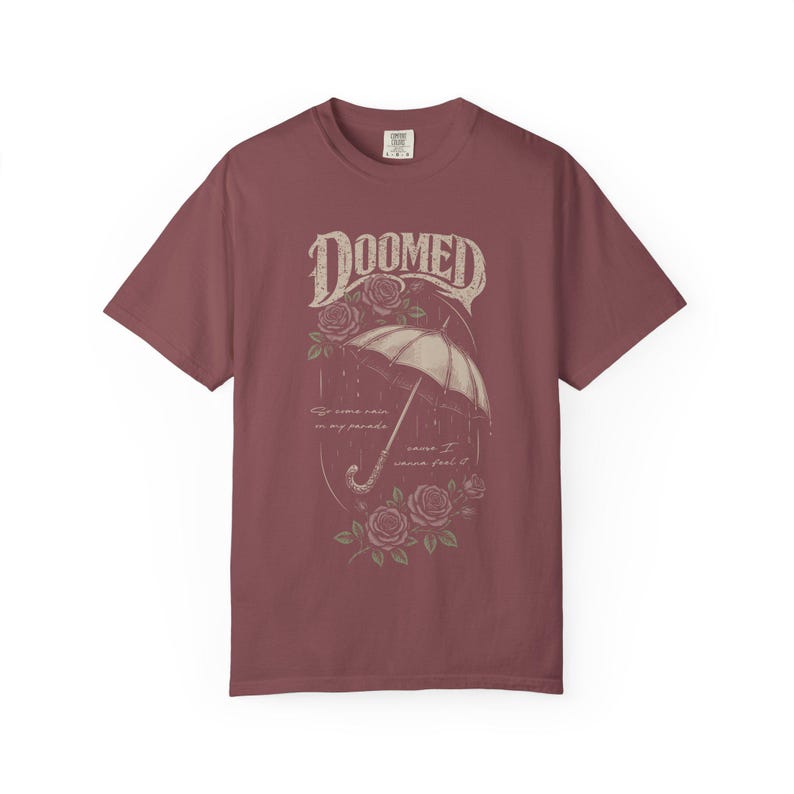 brick color Comfort Colors T-shirt featuring a vintage gothic umbrella illustration with roses and rain details and the word “Doomed” in distressed lettering.