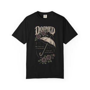 Black color Comfort Colors T-shirt featuring a vintage gothic umbrella illustration with roses and rain details and the word “Doomed” in distressed lettering.