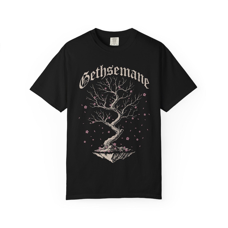May include: A black short-sleeve t-shirt featuring a graphic print of a gnarled tree on a floating island. The word Gethsemane is printed in a gothic font above the tree, which is surrounded by small pink cherry blossoms and falling petals.