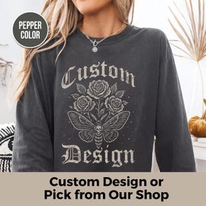 May include: A dark grey long-sleeved shirt with a custom design. The design includes roses, a moth with a skull, and the words "Custom Design". The text "Custom Design or Pick from Our Shop" is at the bottom.