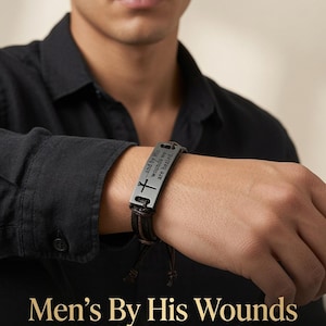 Könnte beinhalten: Ein dunkelbraunes Lederarmband mit einer rechteckigen schwarzen Metallplatte, die mit einem Kreuzsymbol und dem Text "...and by His wounds we are healed." graviert ist. Das Armband verfügt über verstellbare Lederbänder und einen Metallverschluss.