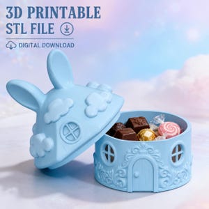 Könnte beinhalten: Ein hellblauer 3D-druckbarer STL-Datei-Digital-Download-Behälter in Form eines kleinen Hauses mit abnehmbarem Deckel, der mit Hasenohren und Wolkenmotiven verziert ist. Die Basis zeigt Tür- und Fensterdetails und ist mit verschiedenen Pralinen gefüllt.