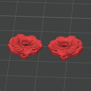 K&ouml;nnte beinhalten: Zwei identische rote Anh&auml;nger in Rosenform mit geschichteten Bl&uuml;tenbl&auml;ttern und einer kleinen kreisf&ouml;rmigen &Ouml;se an der Unterseite zur Befestigung. Das Design zeigt eine dreidimensionale Blumenstruktur mit wirbelnden Bl&uuml;tenblattdetails.