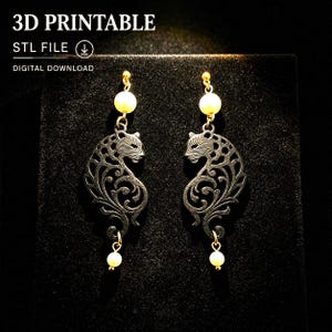 Pode incluir: Um par de brincos com uma silhueta de pantera em filigrana preta com uma pérola branca no topo e na base de cada peça. O texto 3D PRINTABLE STL FILE DIGITAL DOWNLOAD é visível na parte superior da imagem.