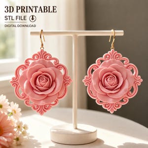 Op de afbeelding: Een paar roze roosvormige oorbellen met sierlijke krulwerkframes, hangend aan goudkleurige haken. De tekst 3D PRINTABLE STL FILE DIGITAL DOWNLOAD is zichtbaar linksboven in de afbeelding, wat duidt op een digitaal ontwerpbestand.