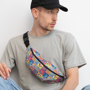 May include: A person wearing a grey t-shirt and a black baseball cap is wearing a colorful fanny pack with a geometric pattern. The fanny pack has a black strap and a zipper.