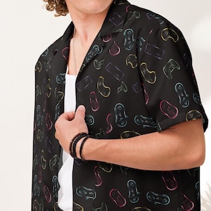 以下が含まれることがあります： カラフルなネオンのゲームパッド柄の黒い半袖ボタンダウンシャツ