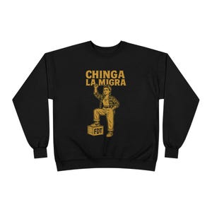 May include: Black sweatshirt featuring a graphic of a person standing on a box, with the text "CHINGA LA MIGRA" above and "FDT" on the box. The person is wearing a plaid shirt and trousers.