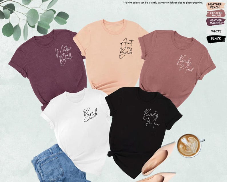 May include: A collection of t-shirts in various colors, including maroon, peach, white, and black. Each shirt features elegant script text, with phrases like "Mother of the Bride," "Aunt of the Bride," "Bridesmaid," "Bride," and "Bridesman."