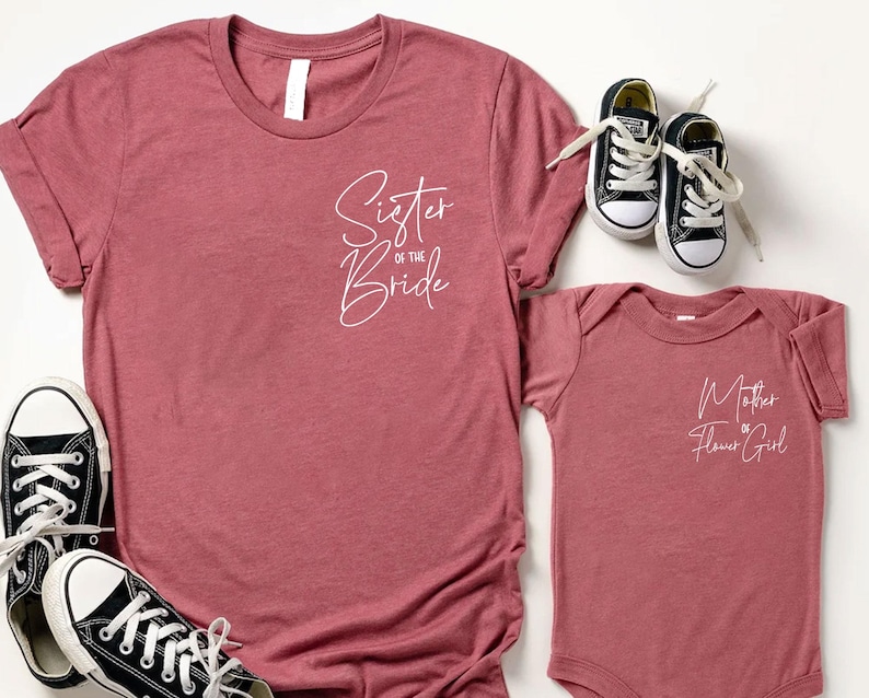 May include: A dusty rose t-shirt with the text "Sister of the Bride" and a matching baby onesie with "Mother of the Flower Girl" printed on it. Black and white sneakers are also in the image.