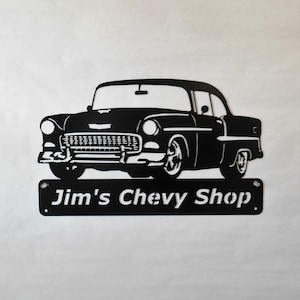 May include: Black metal silhouette of a 1950s Chevrolet car with the text "Jim's Chevy Shop" below it.