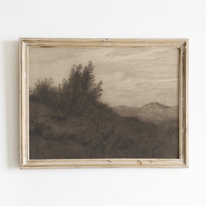 May include: A sepia-toned landscape print in a distressed gold frame. The artwork depicts a hillside with trees and a mountain range under a cloudy sky. The overall aesthetic is vintage and rustic, suitable for home decor.