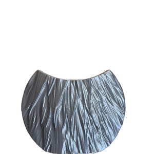 Pode incluir: Uma peça decorativa de cor prateada, texturizada, em forma de crescente. A peça tem uma superfície lisa e brilhante e uma forma ligeiramente curva.