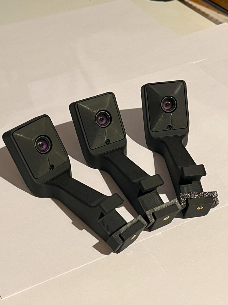 May include: Three black, rectangular devices with a lens and a long handle. Each device has a small, circular lens. The handles have a rectangular base. The devices are arranged in a row.