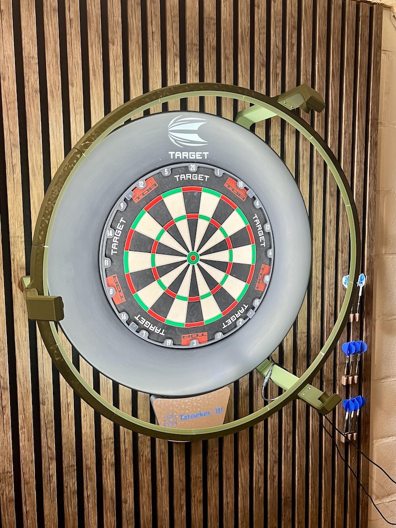 Op de afbeelding: Een dartbord met een grijze rand en een groen en rood doelontwerp. Het dartbord is gemonteerd op een houten muur en heeft een groen metalen frame. De merknaam "Target" is zichtbaar op het dartbord.