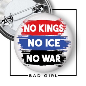 May include: A white button with the text "NO KINGS, NO ICE, NO WAR" in white letters over red, blue, and black brushstrokes. The words "BAD GIRL" are at the bottom in white text.