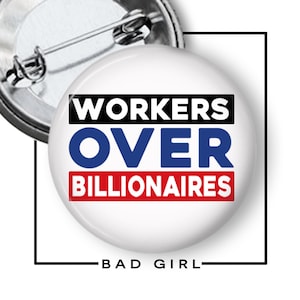 May include: A white button with the text "WORKERS OVER BILLIONAIRES" in black, blue, and red. The button has a metal pin back and the words "BAD GIRL" are at the bottom.