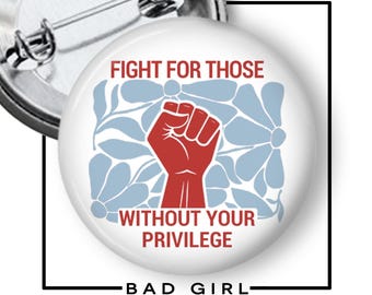 May include: A circular pin-back button featuring a red raised fist graphic centered over a light blue floral pattern. The text reads FIGHT FOR THOSE WITHOUT YOUR PRIVILEGE in red capital letters. The back of the button shows a metal pin mechanism.