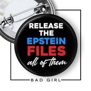 May include: A black button with the text "RELEASE THE EPSTEIN FILES all of them" in white, blue, and red. The button has a pin back and the words "BAD GIRL" are at the bottom.