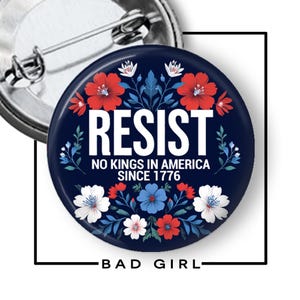 May include: A circular pin-back button with a dark blue background featuring red, white, and blue floral illustrations. The text reads RESIST, NO KINGS IN AMERICA SINCE 1776 in white capital letters. The back shows a silver metal pin mechanism.