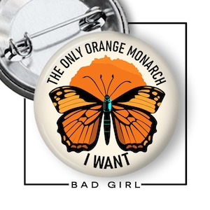 May include: A round pin-back button featuring a graphic of an orange and black monarch butterfly centered over an orange circle. The text THE ONLY ORANGE MONARCH I WANT is printed in black capital letters around the butterfly. The pin back is visible.