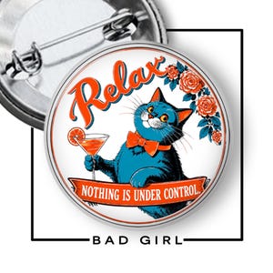 May include: A circular pin-back button featuring a blue cat wearing an orange bow tie, holding a cocktail glass with a citrus slice. The text reads Relax and Nothing is under control, surrounded by orange roses on a white background.