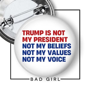 May include: A round white pin-back button featuring red text that reads TRUMP IS NOT MY PRESIDENT and blue text that reads NOT MY BELIEFS, NOT MY VALUES, NOT MY VOICE. The back of the pin shows a silver metal pin mechanism with a safety clasp.