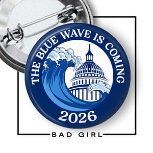 May include: A circular pin-back button featuring a dark blue background with a white illustration of a large ocean wave crashing against a domed building. The text reads THE BLUE WAVE IS COMING in an arc at the top and 2026 at the bottom in white.