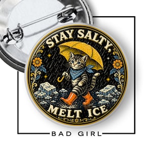 May include: A round pin-back button featuring a tabby cat wearing a blue bandana and orange rain boots while holding a yellow umbrella. The background shows rain, ice, and flowers. The text reads STAY SALTY, MELT ICE in a circular border.