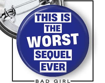 May include: A round, blue button with the text "THIS IS THE WORST SEQUEL EVER" in white block letters. The words are stacked on top of each other. The button also has the text "BAD GIRL" at the bottom.