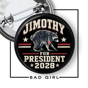 May include: A round pin-back button featuring a black background with a central illustration of a raccoon wearing a stars and stripes bandana. The text reads JIMOTHY FOR PRESIDENT 2028 in a distressed white font, accented by red lines and white stars.