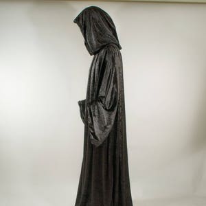 May include: A long black velvet robe with a large hood. The robe is worn by a person standing with their back to the camera.