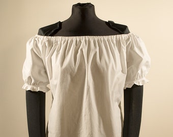 May include: A white off-the-shoulder peasant blouse with short puffed sleeves. The blouse is on a black mannequin with a black stand.