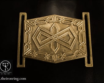 May include: A gold-colored metal belt buckle with an intricate geometric design. The buckle has a square shape with rounded corners and features a repeating pattern of interlocking shapes.