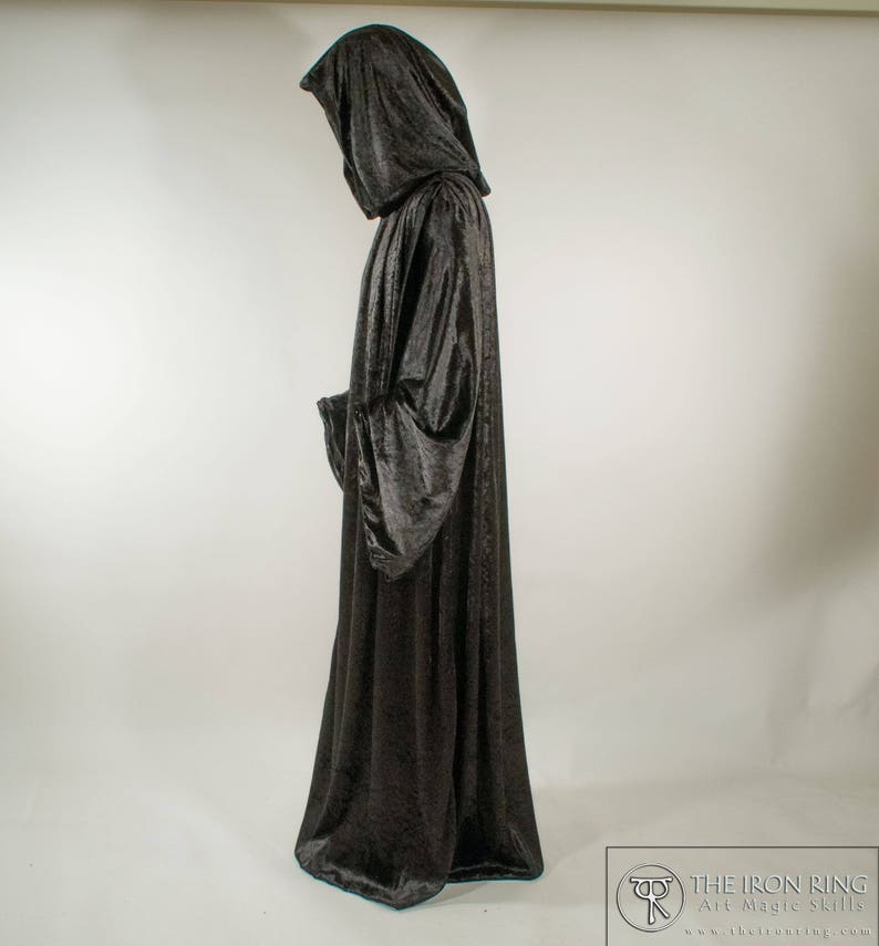 May include: A long black velvet robe with a large hood. The robe is worn by a person standing with their back to the camera.