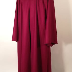 May include: A long, burgundy hooded robe with a silver clasp at the neck. The robe is made of a soft, flowing fabric and has a simple, elegant design.