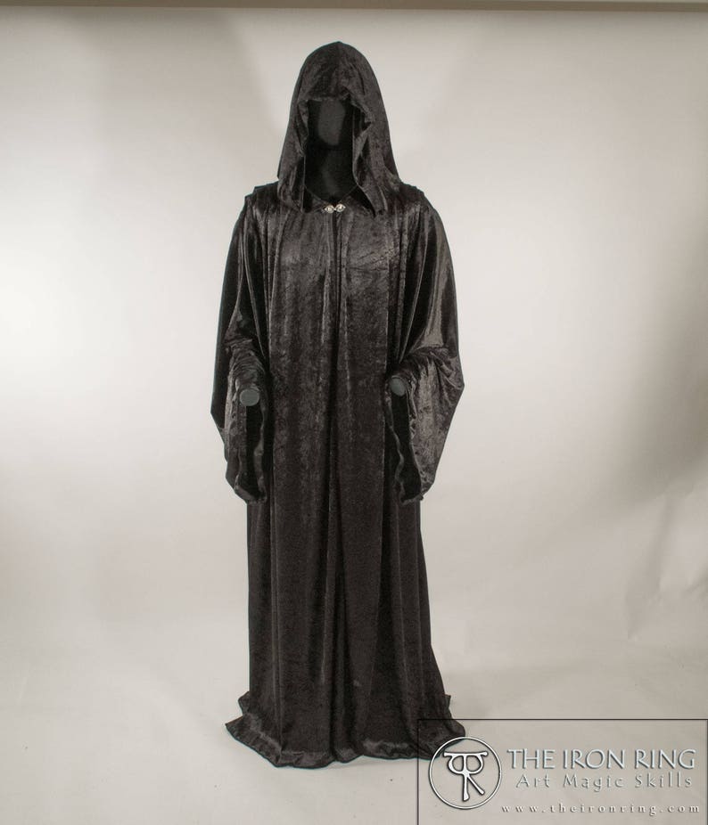 May include: A long black velvet robe with a large hood. The robe has a decorative clasp at the neck.