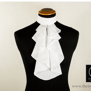 Op de afbeelding: Een witte geplooide kraag met een staande kraag, gedragen door een zwart manikin. De kraag is gemaakt van een stevige, witte stof met een subtiel gestreept patroon. De kraag is een klassieke stijl, perfect voor formele gelegenheden.
