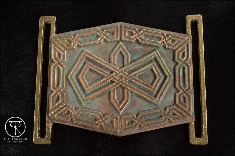 May include: A bronze belt buckle with a geometric design. The buckle has a green patina and is decorated with intricate patterns.