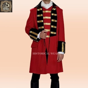 Puede incluir: Una chaqueta roja con ribetes negros y dorados. La chaqueta tiene un cuello alto y un cierre de doble botonadura. Las mangas tienen ribetes dorados y negros. La chaqueta es de estilo histórico.