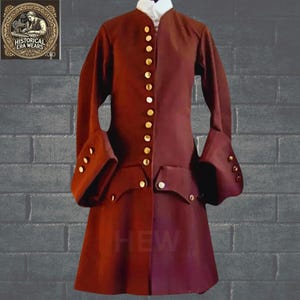 May include: A maroon-colored coat with gold buttons and a stand-up collar. The coat has long sleeves with cuffs and two pockets on the front. The coat is shown against a brick wall.