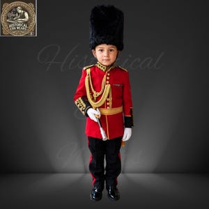 May include: A red military-style tunic with gold braided cord, gold buttons, and black cuffs, paired with black trousers featuring a red side stripe. The outfit includes a tall black bearskin hat, white gloves, and a gold-tipped baton accessory.