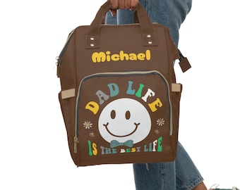 May include: Brown diaper bag with a smiley face and the text "Dad Life is the Best Life". The bag has a name tag that says "Michael".
