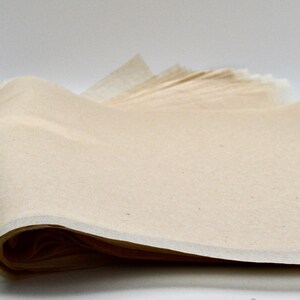 May include: A stack of off-white tissue paper, folded and ready for use. The paper is smooth and has a slightly textured surface.