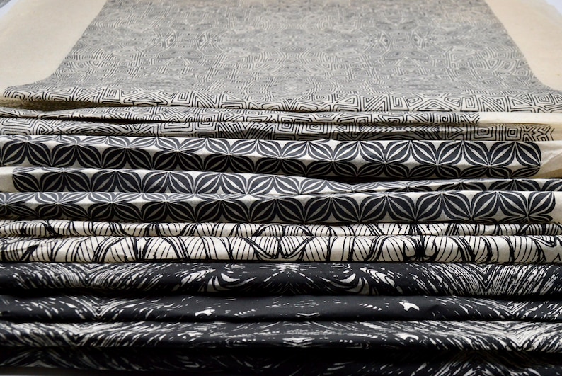 May include: A stack of fabric with different black and white geometric patterns. The fabric is folded and layered, creating a visual texture.