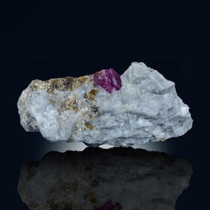 May include: A bright pink ruby crystal embedded in a matrix of white and gray rock. The ruby is a vibrant red color and has a sharp, well-defined crystal shape.